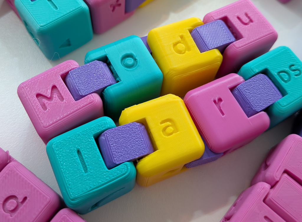 Modular DS-branded infinity cubes (fidget toys) in pink, yellow, teal, and purple.